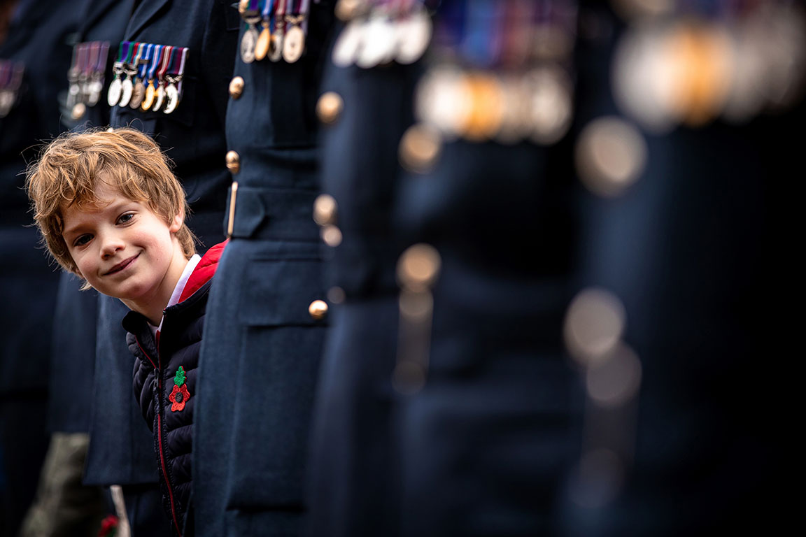 Image shows child looking along row of personnel during Remembrance service.